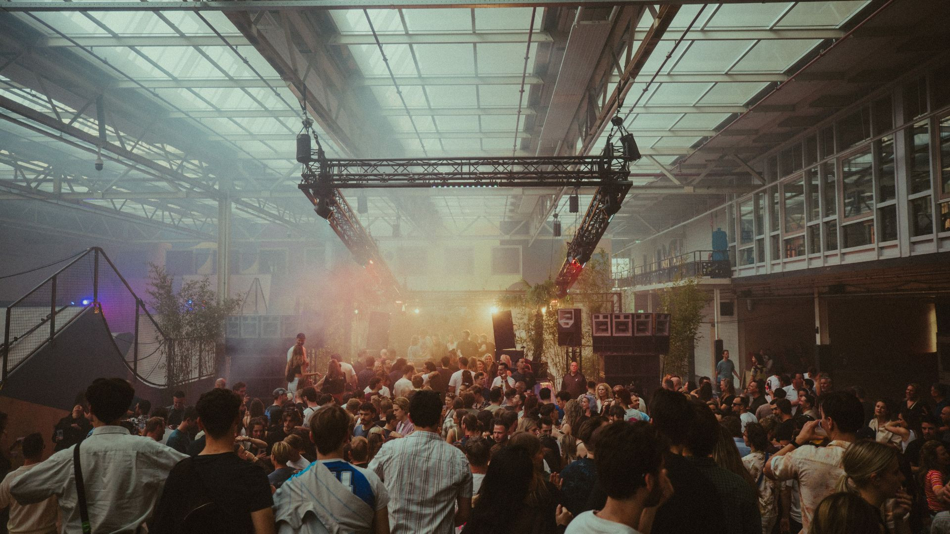 Crowded indoor music festival with stage and vibrant atmosphere.