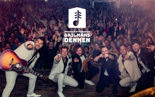 A band dressed in light-colored suits poses in front of a large cheering crowd at an open-air theater, with a logo reading "Openluchttheater Brilmans Dennen" superimposed above them.