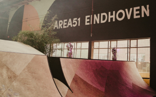 Indoor skatepark with ramps, labeled Area51 Eindhoven, features vibrant lighting and decor.